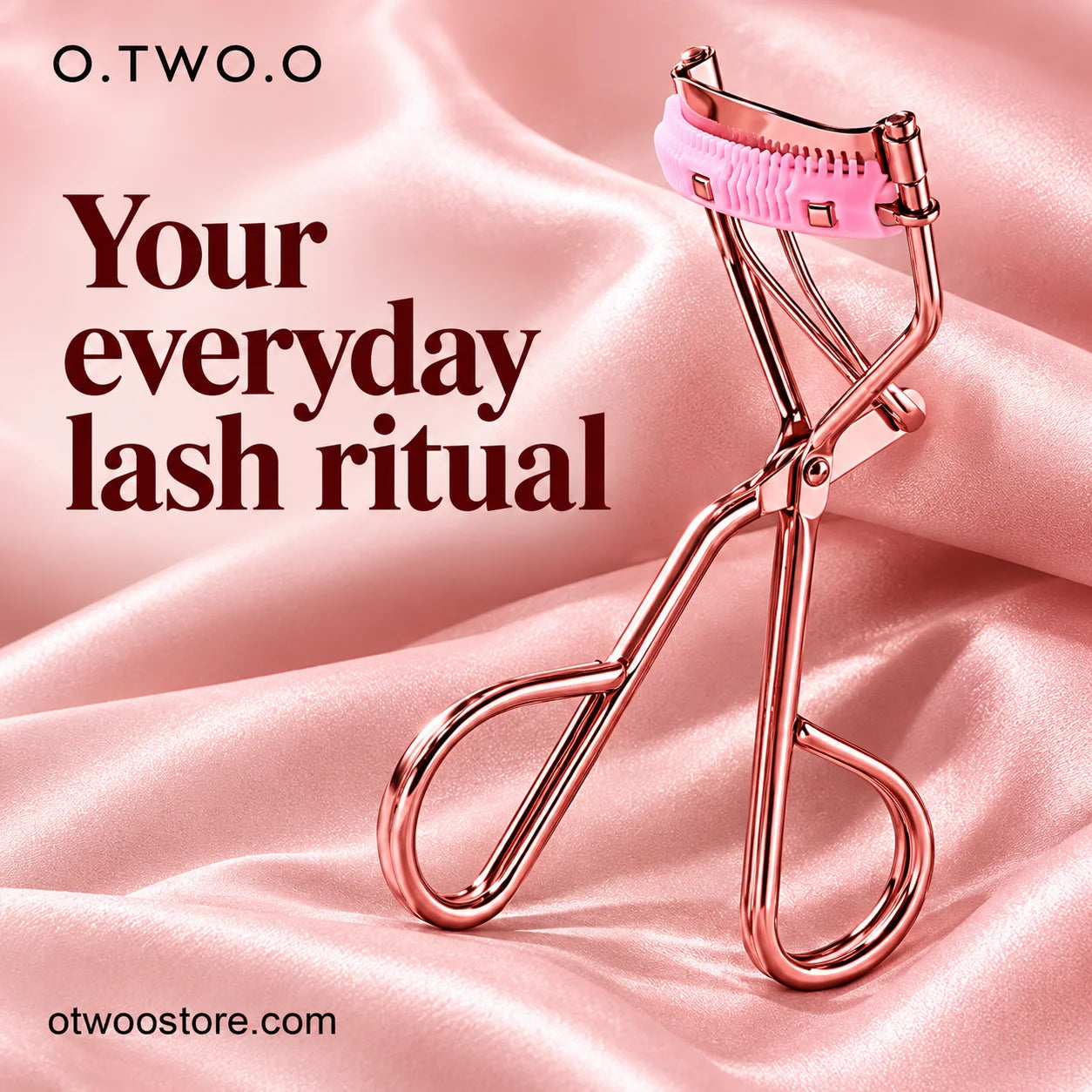 Rose-gold comb eyelash curler styled on softly folded pink satin